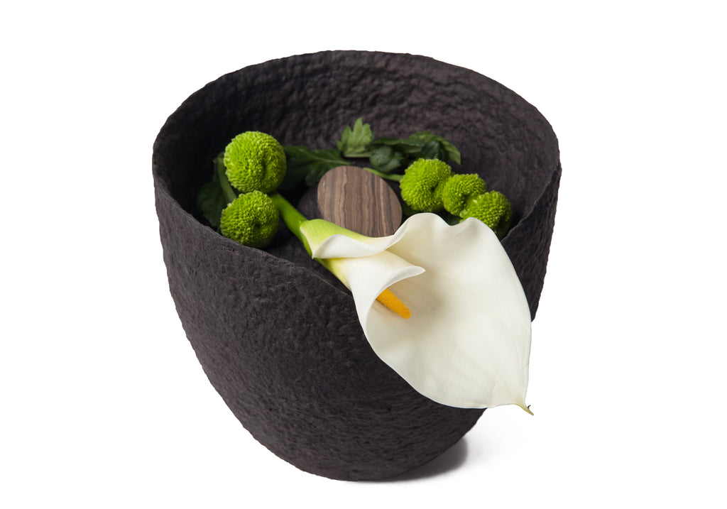 Picture of a black ovoid biodegradable cremation urn on sale at Muses Design Urns. View with flowers A.