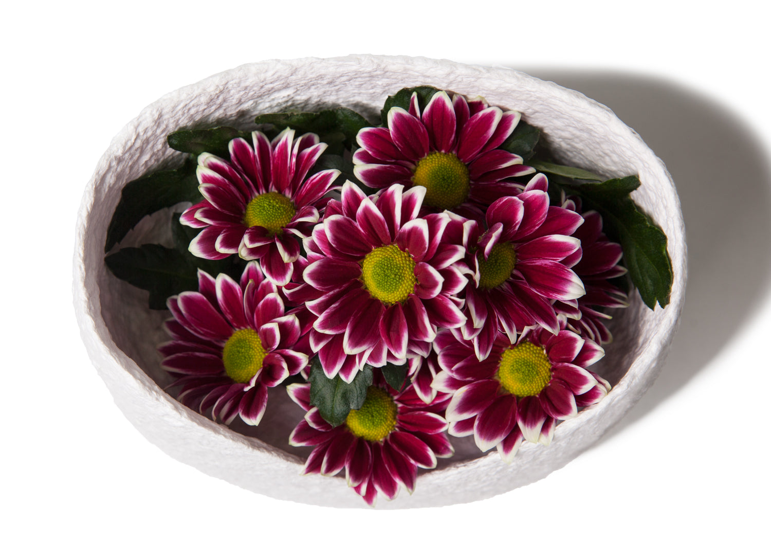 Picture of a white biodegrdable coton fibre cremation urn resembling a Moses basket for children on sale at Muses Design Urns. Top View with flowers.